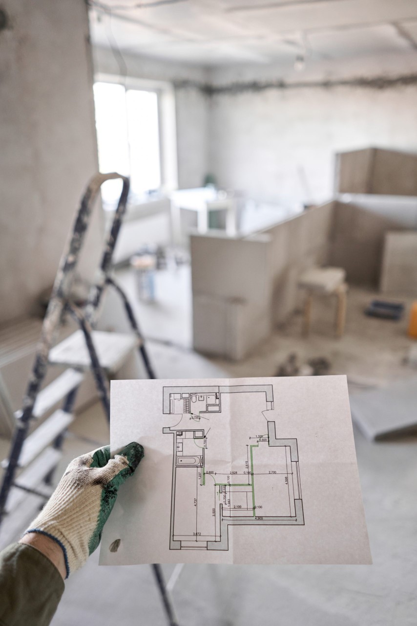 man holding blueprint inside house being renovated